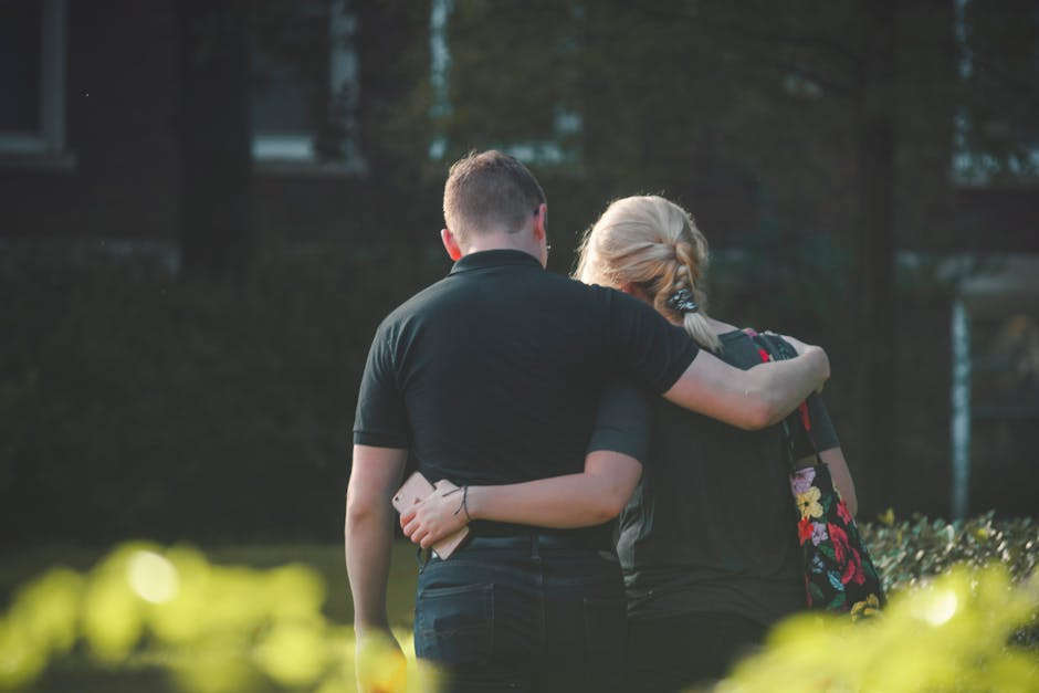 A couple embraces while walking in a sunlit park, conveying love and togetherness.